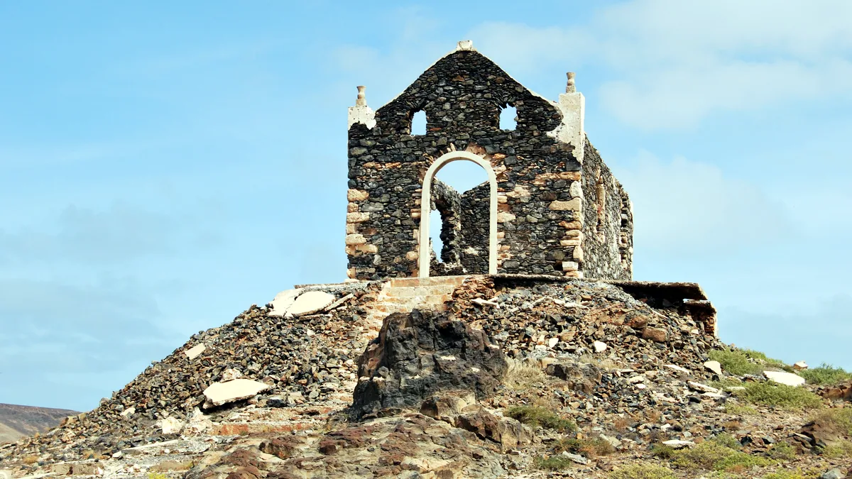 The stone arches of an old church ruin stand in a dry open field.
