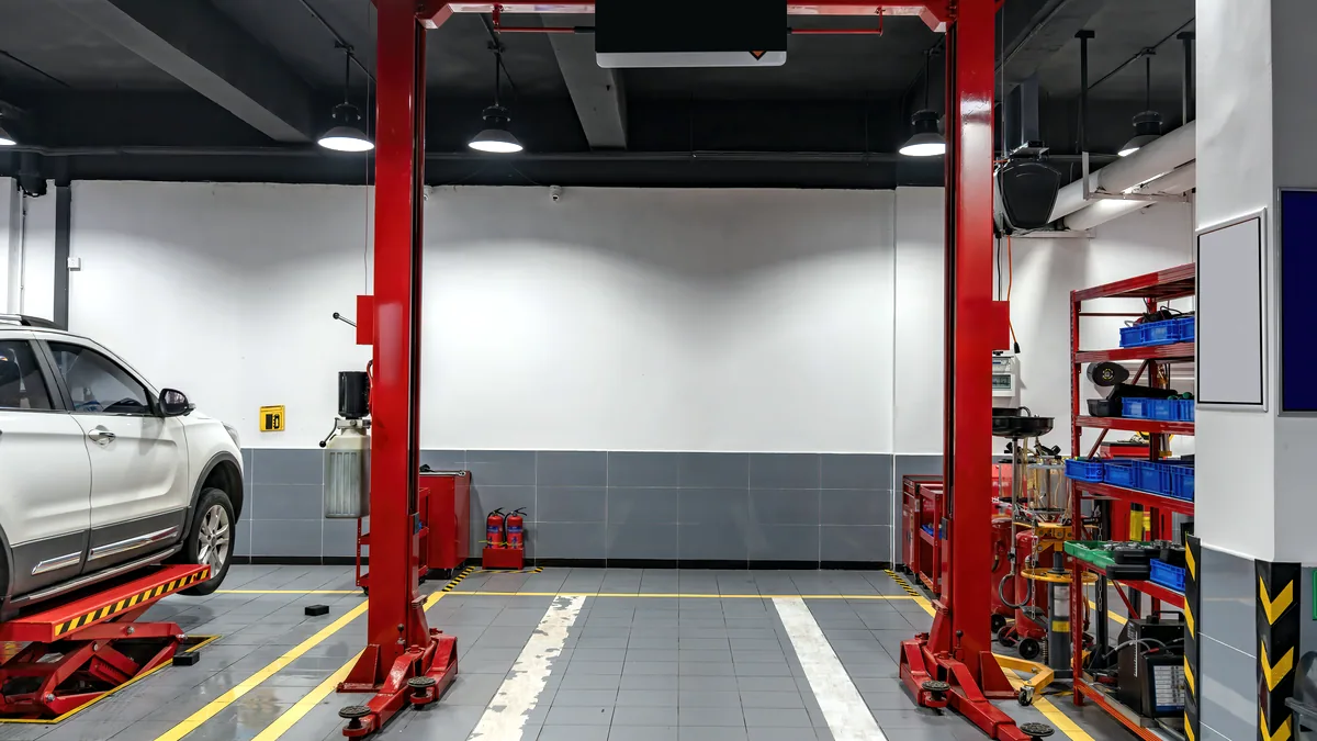 A car rests on a lift inside a clean service bay with tools nearby.