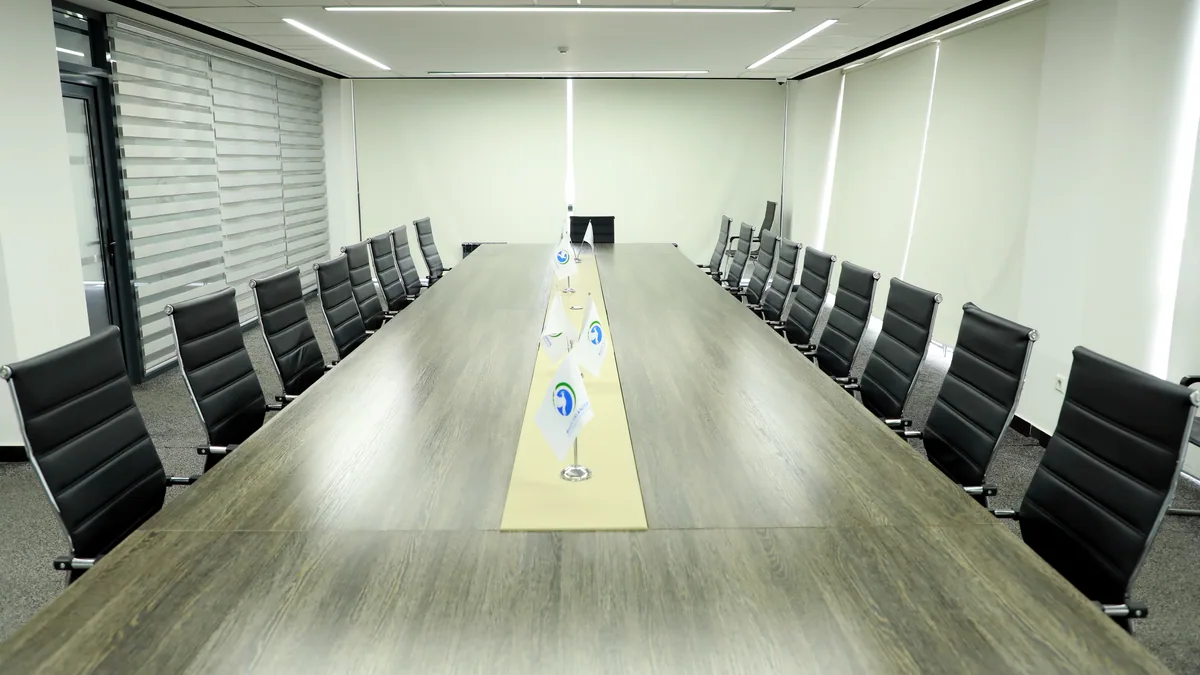 An empty conference room with a long table lined with papers and glasses.