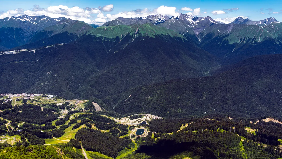 A dry valley floor sits between steep brown mountains under a clear sky.